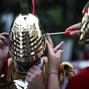 A man dressed as ancient Roman adjusts his helmet before a procession as part of Holy