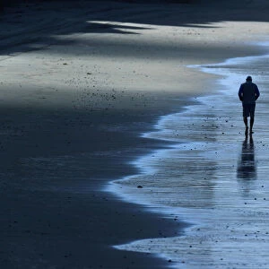 A man goes for an early morning walk along the ocean in Solana Beach, California