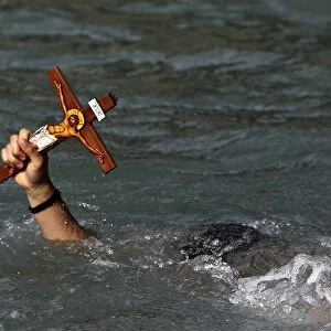 A man holds a cross after a competition to retrieve it from the water during Epiphany day