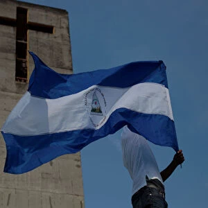 A man holds up a Nicaraguan flag during a protest march to demand an end to violence in