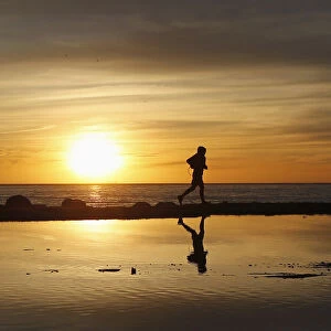 A man jogs during a sunset along the coast in Valparaiso city