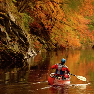 A man paddles his canoe down the river Garry near Killiekrankie, Scotland