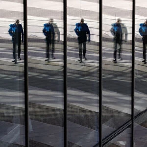 A man is reflected in the glass facade of the Post Tower, the headquarters of German postal