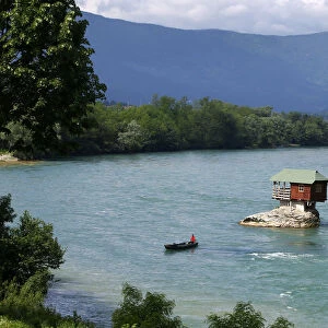 A man rows a boat near a tiny house build on a rock on the river Drina is seen near