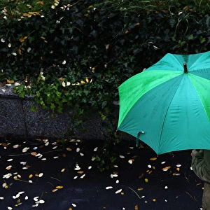 A man shelters from the rain underneath an umbrella in Madrid