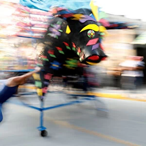 Man spins a traditional bull figure surrounded by fireworks, known as El Torito