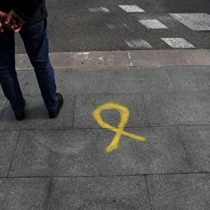 A man stands near a yellow ribbon, the symbol used to demand the release of jailed