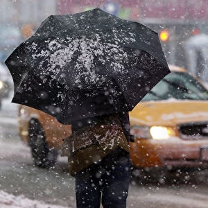 Man stands under a snow-covered umbrella at Times Square in New York