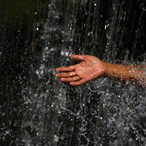 A man takes out his hand throughout the waterfall at Muhan Pokhari in Bhaktapur