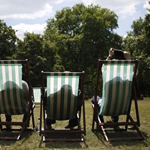 A man takes his jacket off as he settles into his deck chair on a sunny day in St