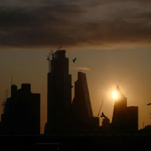 A man takes a photograph of the skyline as the sun rises behind the city of London A man takes a photograph of the skyline as the sun rises behind the city of London