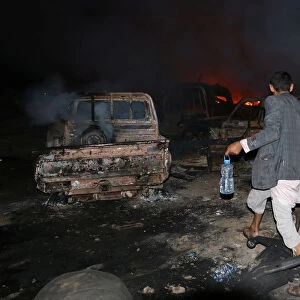 A man walks in front of a fire that broke out at the site of a Saudi-led air strike which