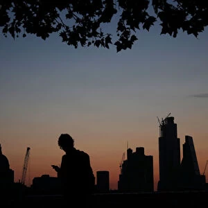 A man walks past the city of London financial district as dawn breaks in London