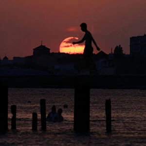 A man walks along a pier during sunset in Yevpatoriya