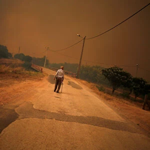 A man walks on the road as the fire approaches Pedreira, near Silves