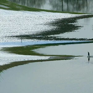 A MAN WALKS THROUGH THE WATER ON THE FLOODED BANKS OF THE RIVER NaB NEAR THE