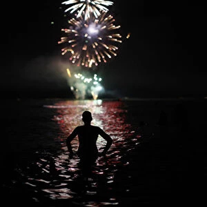 A man watches fireworks as he takes a bath in the Mediterranean Sea on San Juans night