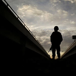 A member of the Mexican National Guard stands near the border fence between Mexico and the U