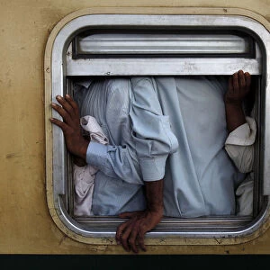 Men are seen at the window of a train as they make their way home, ahead of the Eid