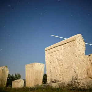A meteor streaks past stars in the night sky above medieval tombstones during A meteor streaks past stars in the night sky above medieval tombstones during