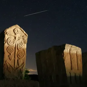 A meteor streaks past stars in the night sky above medieval tombstones in Radmilje near A meteor streaks past stars in the night sky above medieval tombstones in Radmilje near