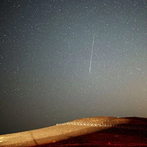 A meteor streaks across the sky in the early morning during the Perseid meteor shower in