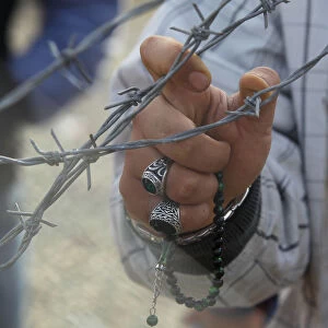 Migrant grips barbed wire fence at Macedonian-Greek border near Gevgelija