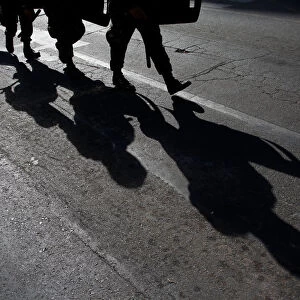 Military policemen cast their shadows as they march toward a protest to mark International