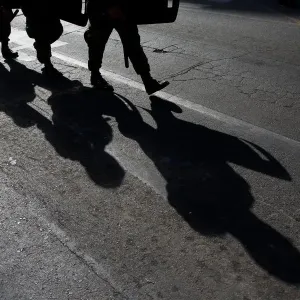 Military policemen cast their shadows as they march toward a protest to mark International Military policemen cast their shadows as they march toward a protest to mark International