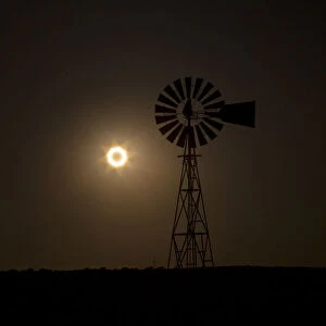 The moon passes between the sun and the earth behind a windmill near Albuquerque