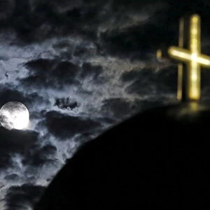 The moon rises above a church on the Greek island of Santorini, Greece