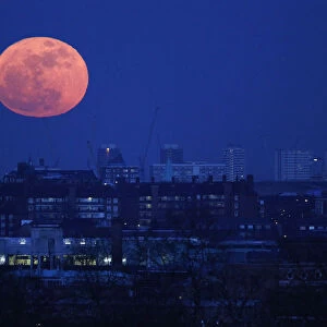 The moon rises over east London