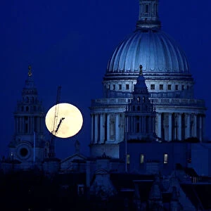 A full moon rises behind St Pauls Cathedral London