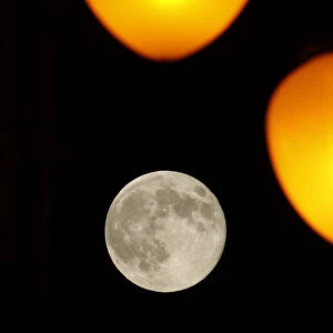 The full moon rises behind street lamps in Tbilisi