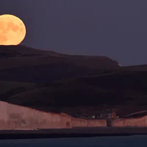 The moon is seen rising behind the Seven Sisters Cliffs at Birling Gap in East Sussex The moon is seen rising behind the Seven Sisters Cliffs at Birling Gap in East Sussex