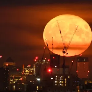 The full moon is seen rising behind skyscrapers at Canary Wharf and the London skyline The full moon is seen rising behind skyscrapers at Canary Wharf and the London skyline
