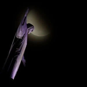 The moon is seen next to the statue of Christ the Redeemer during a total lunar eclipse