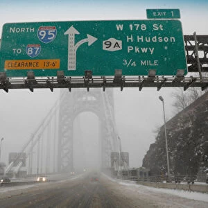 A nearly empty snow-covered roadway entrance to the George Washington Bridge between New