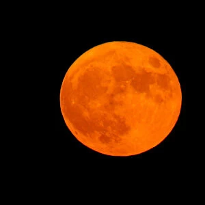 An orange full moon rises in the Strait of Gibraltar
