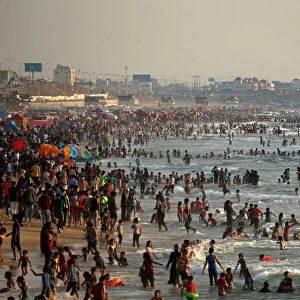 Palestinians bathe in the Mediterranean Sea as they escape from the summer heat, in