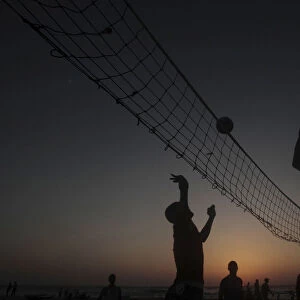 Palestinians play volleyball during the sunset at the sea of Gaza City
