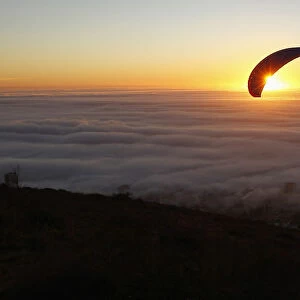 Paragliders take in the last of the days light as a seasonal fog engulfs Cape Town
