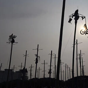 A participant pulls down a bicycle from the top of a greased pole during the Panjat