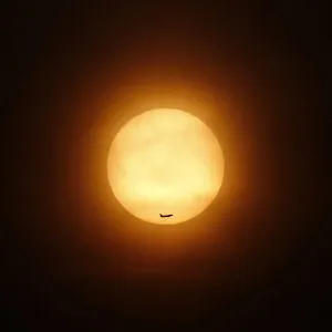 A passenger jet flies past the setting sun in Shanghai