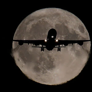 A passenger plane, with a full Harvest moon seen behind, makes its final landing approach