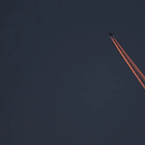 A passenger plane leaves behind contrails as it flies in the skies over London Luton