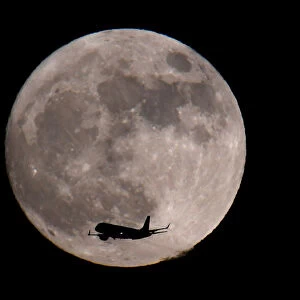 A passenger plane, with a supermoon full moon seen behind
