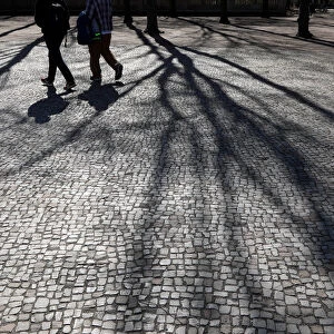 Two pedestrians cast their shadows during a sunny day in Berlin