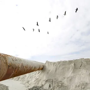 Pelicans fly above dredging equipment at St. Augustine Beach in Florida Pelicans fly above dredging equipment at St. Augustine Beach in Florida