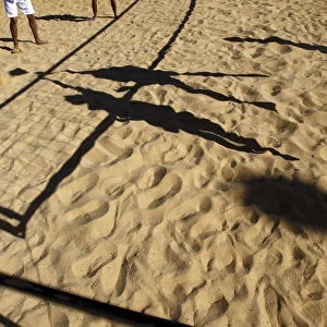 People cast shadows on the sand as they compete in a volleyball game in Jerusalem